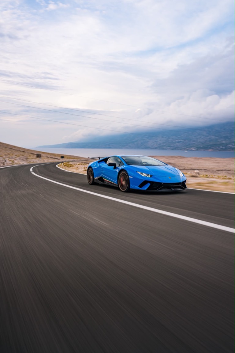 The car cornering on a coastal road above the sea.